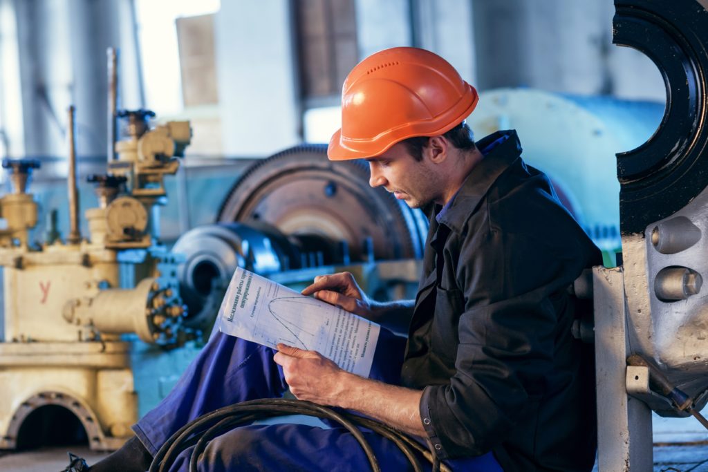 Worker on industry studying manual instructions for repair turbine.